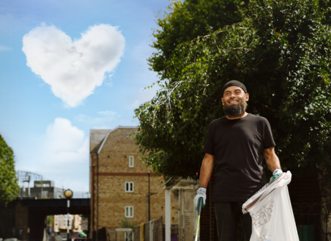 A man litter picking with a cloud heart in the background